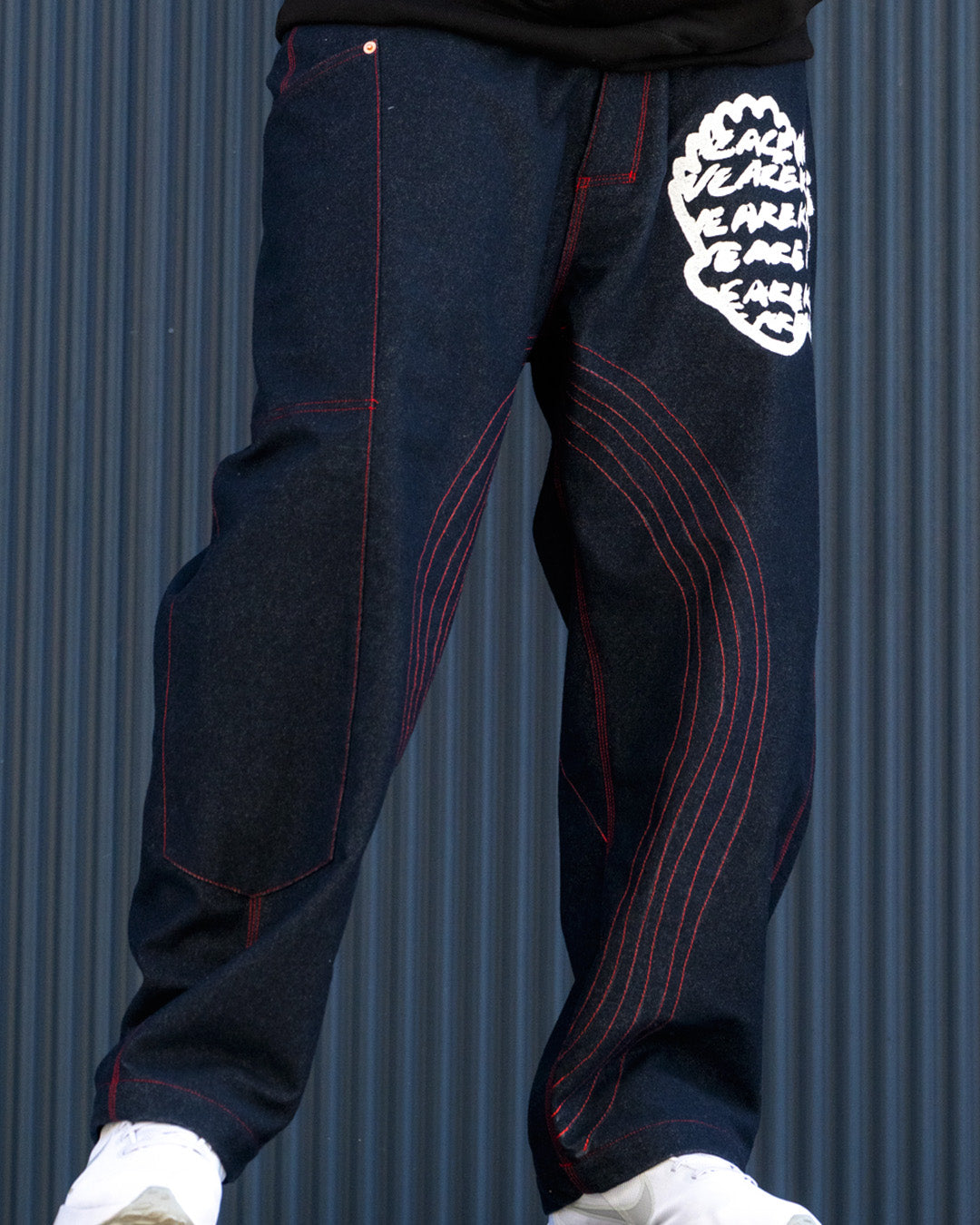 Dark blue pants with red stitching and a white logo on a gray background